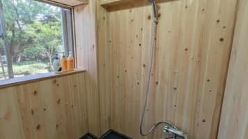 A wooden-paneled room with a shower, a bench, and a window.
