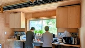 Une cuisine de taille réduite, dotée de meubles en bois, d’une fenêtre et d’un plan de travail sur lequel sont disposés divers objets.
