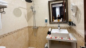 A bathroom with a shower, toilet, sink, and a mirror. - Crown Luxury Hotel (Hanoi)