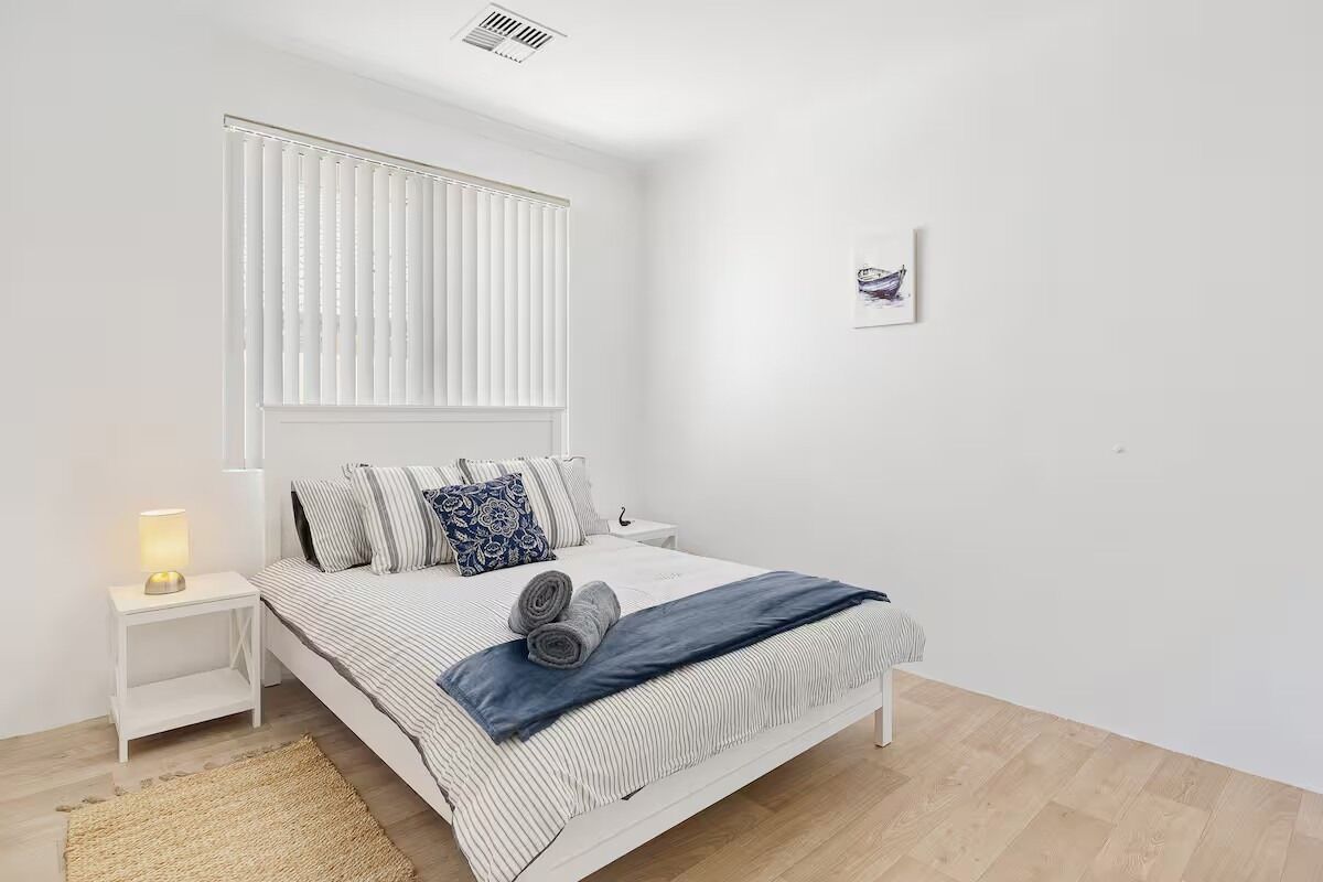 Ein schlicht eingerichtetes Schlafzimmer mit Bett, Nachttisch und einer Wandleuchte.