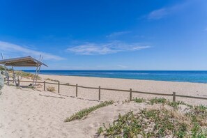 Ein Strand mit einer Holzlattenverkleidung, einem überdachten Bereich und dem Meer im Hintergrund.