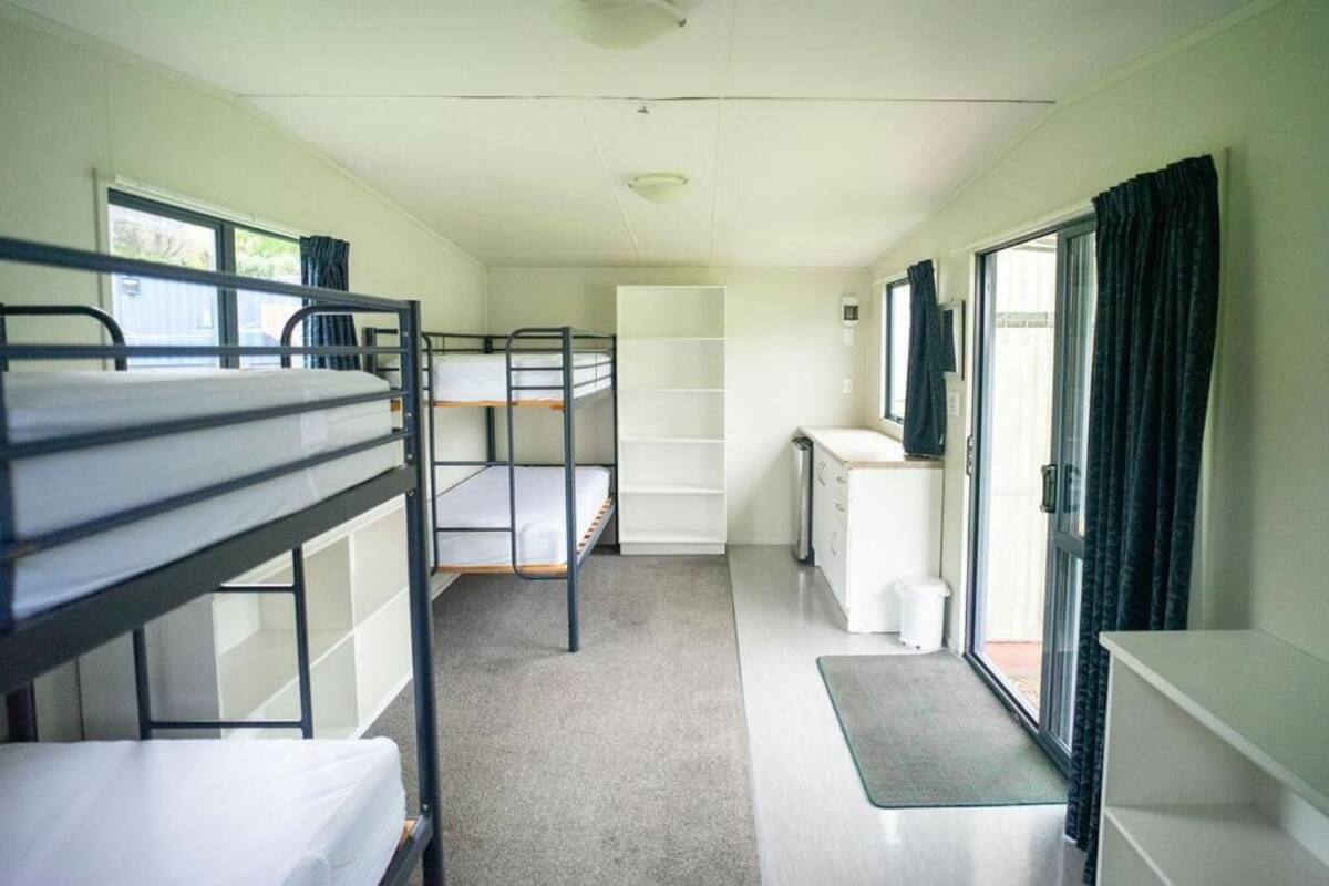 Un dormitorio con literas, una kitchenette pequeña, una ventana y una puerta.