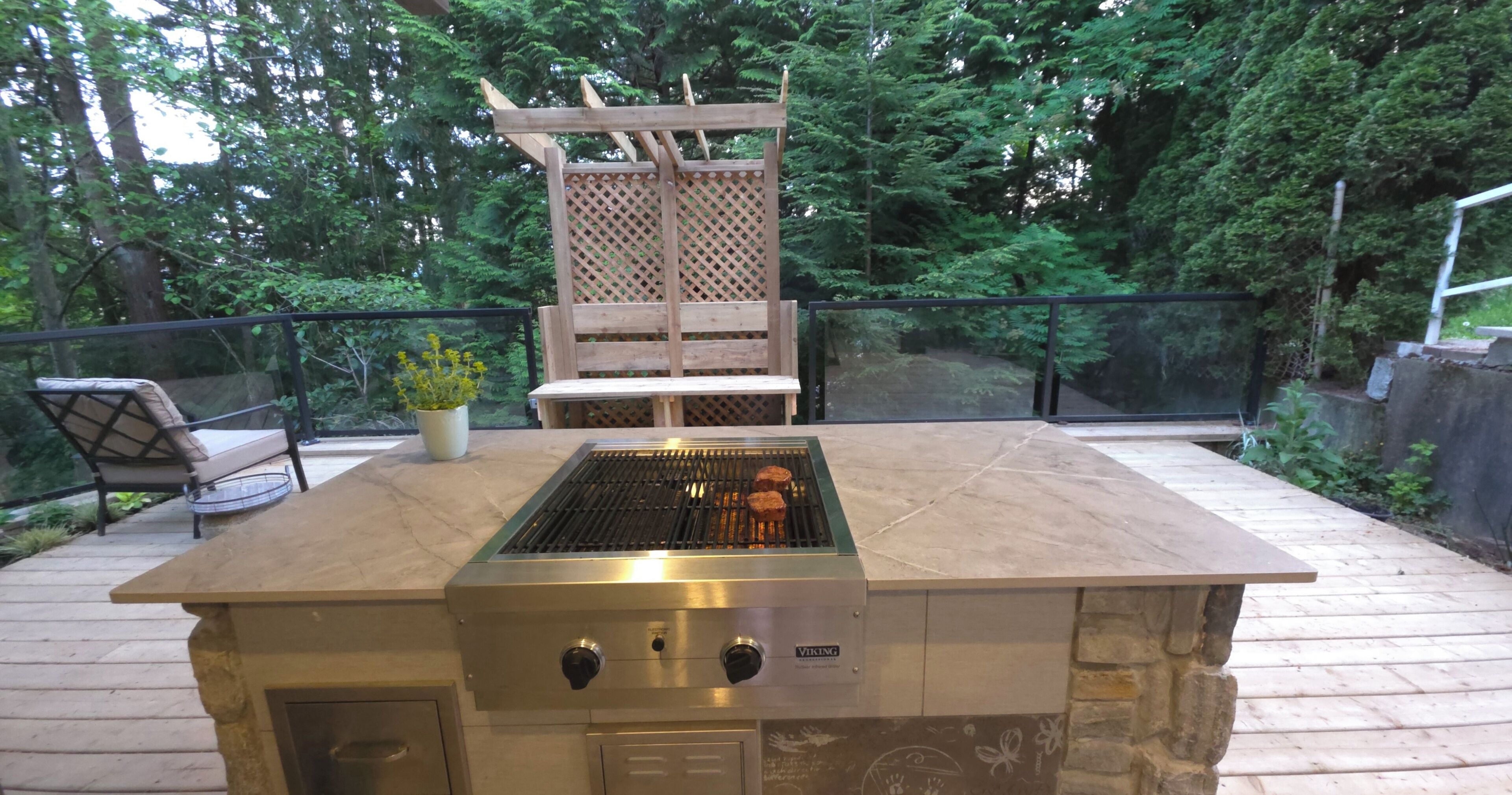 Una cocina exterior con una parrilla empotrada, una mesa de madera y una zona de estar con sillas.