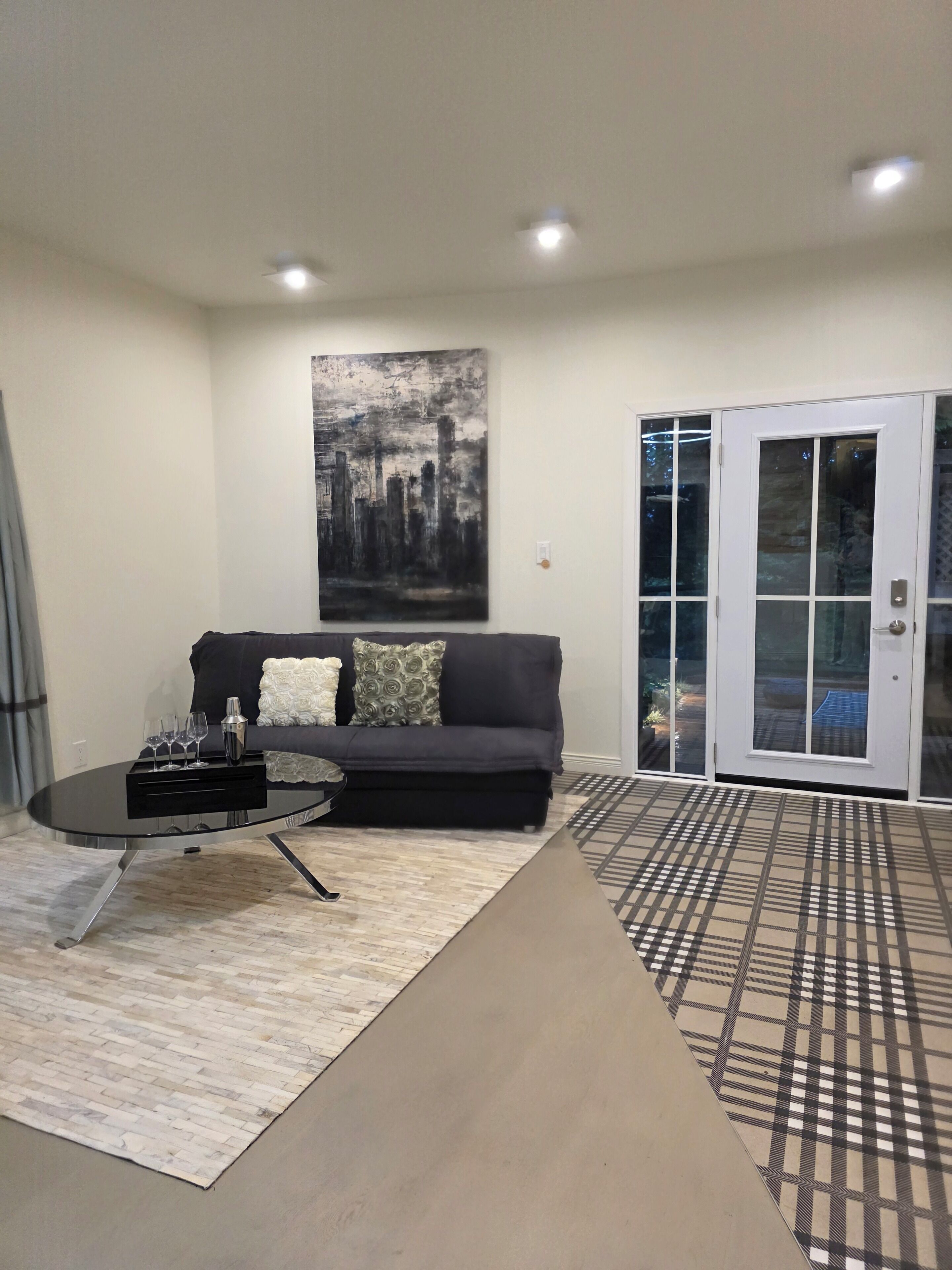 A living room with a sofa, a coffee table, a painting, and a sliding glass door.