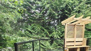 A wooden deck with raised garden beds, a wooden pergola, and a metal railing. - Private Creekside Garden Suite - Patio, Deck, BBQ & Free Parking. Pet Friendly. (North Vancouver)