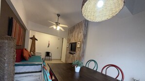 Ein Essbereich mit Holztisch, Stühlen, Deckenventilator und einer gewobenen Lampe.