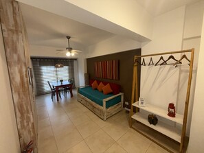 A compact room with a bed, a dining table, chairs, a ceiling fan, and a wall-mounted shelf with a lantern. - Comfortable Apartment Near Salta City Center (Salta)