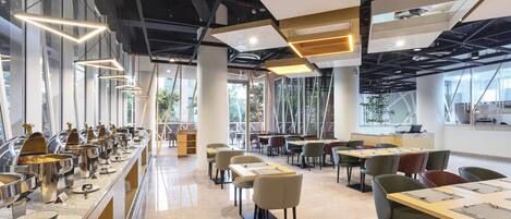 A modern dining area with a buffet line, multiple tables, and chairs.