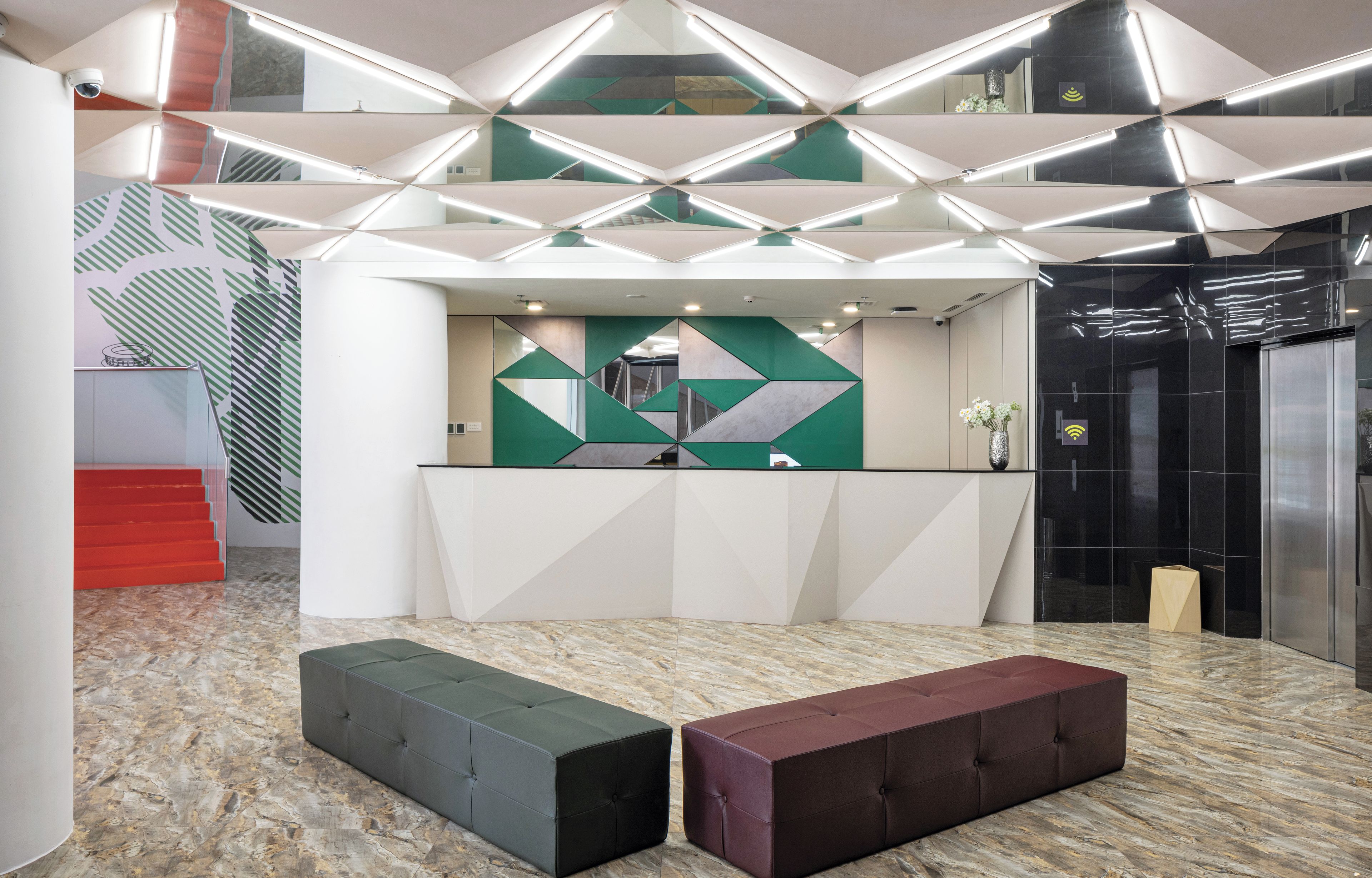 Un área de recepción con pared de diseño geométrico, un mostrador de recepción y piso de mármol.