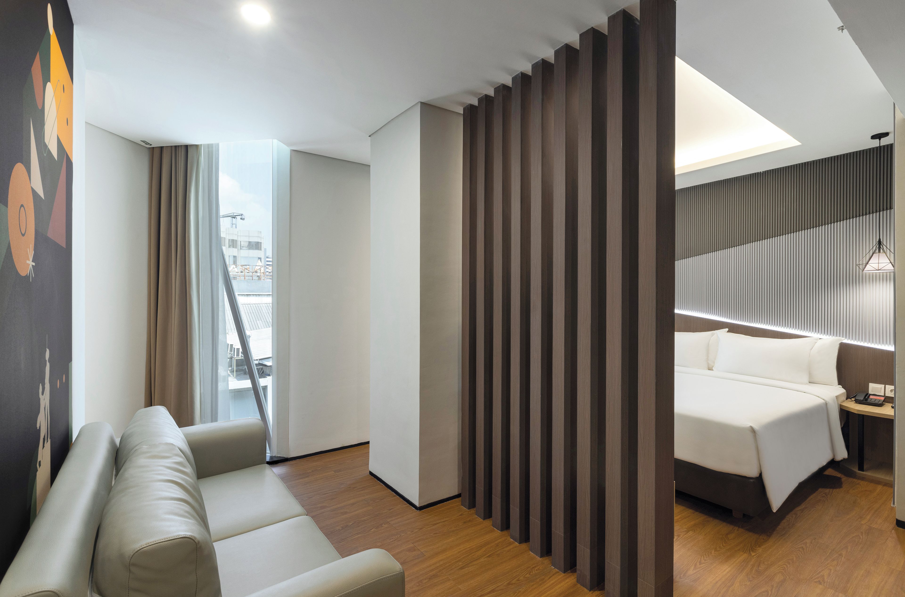 Une chambre d’hôtel avec un lit, un canapé, un bureau et une vue sur la ville.