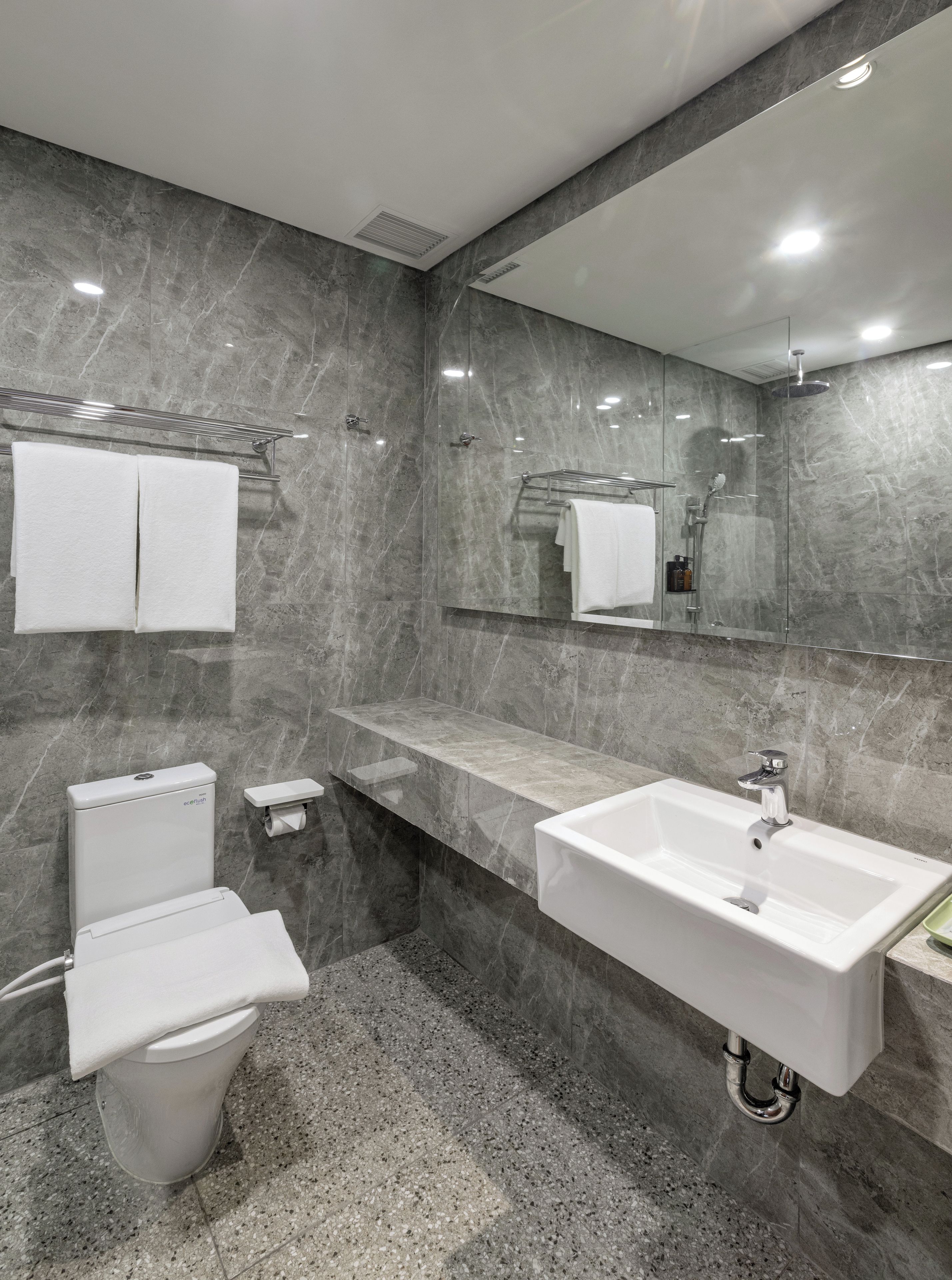 Une salle de bain moderne équipée de toilettes, d’un lavabo et d’une douche.