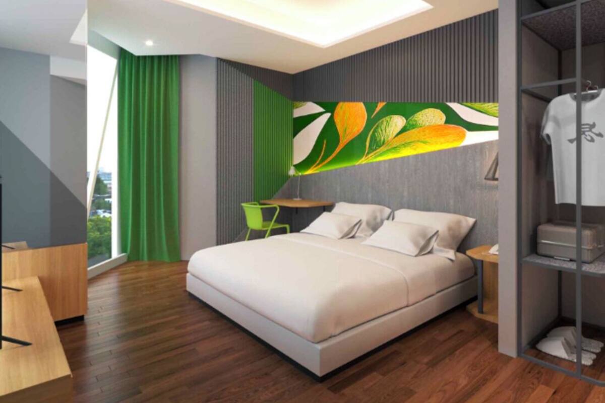 Un dormitorio moderno con cama, una silla verde, un escritorio y un armario.