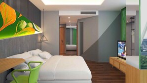 Una habitación de hotel moderna con una cama, un escritorio, una silla, un televisor y un mural grande en la pared.
