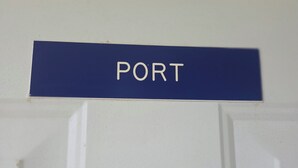 Eine weiße Tür mit einem blauen Schild, auf dem 'PORT' steht.