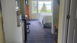 Ein Hotelzimmer mit Bett, Schreibtisch, Stuhl, Fernseher und einem Fenster mit Blick auf Bäume und Wasser.