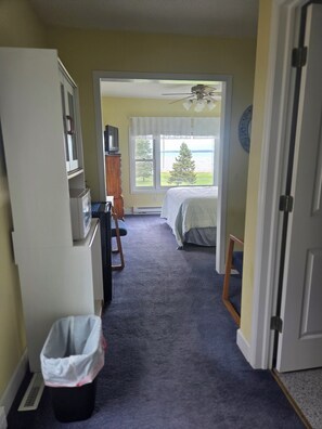 Une chambre d’hôtel équipée d’un lit, d’un bureau, d’une chaise, d’une télévision et d’une fenêtre donnant sur des arbres et l’eau.