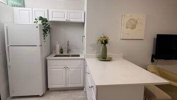 A modern kitchen with white cabinetry, a built-in refrigerator, a sink, and a small island with a bench.