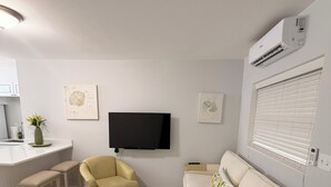 A modern living room with a sofa, armchair, and a TV mounted on the wall.
