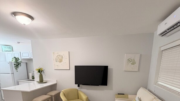 A modern living room with a sofa, armchair, and a flat-screen TV mounted on the wall.