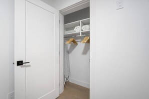 A white closet with shelves, hanging space, and a hanging iron.