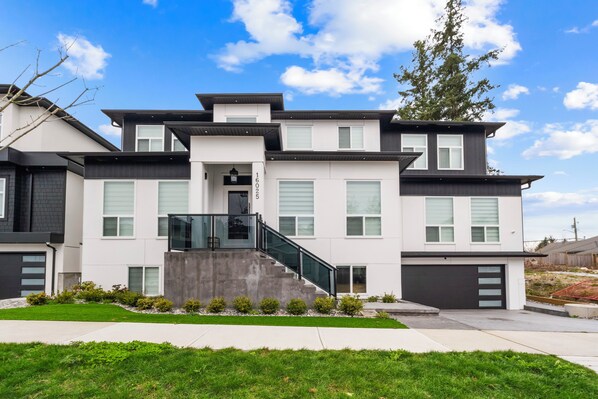 A modern two-story house with a garage, a staircase, and a well-maintained lawn.
