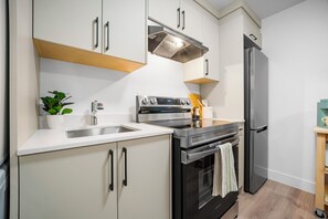 A modern kitchen with white cabinetry, stainless steel appliances, and a wooden countertop.