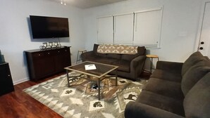 A living room with a sofa, a coffee table, a TV, and a ceiling fan.