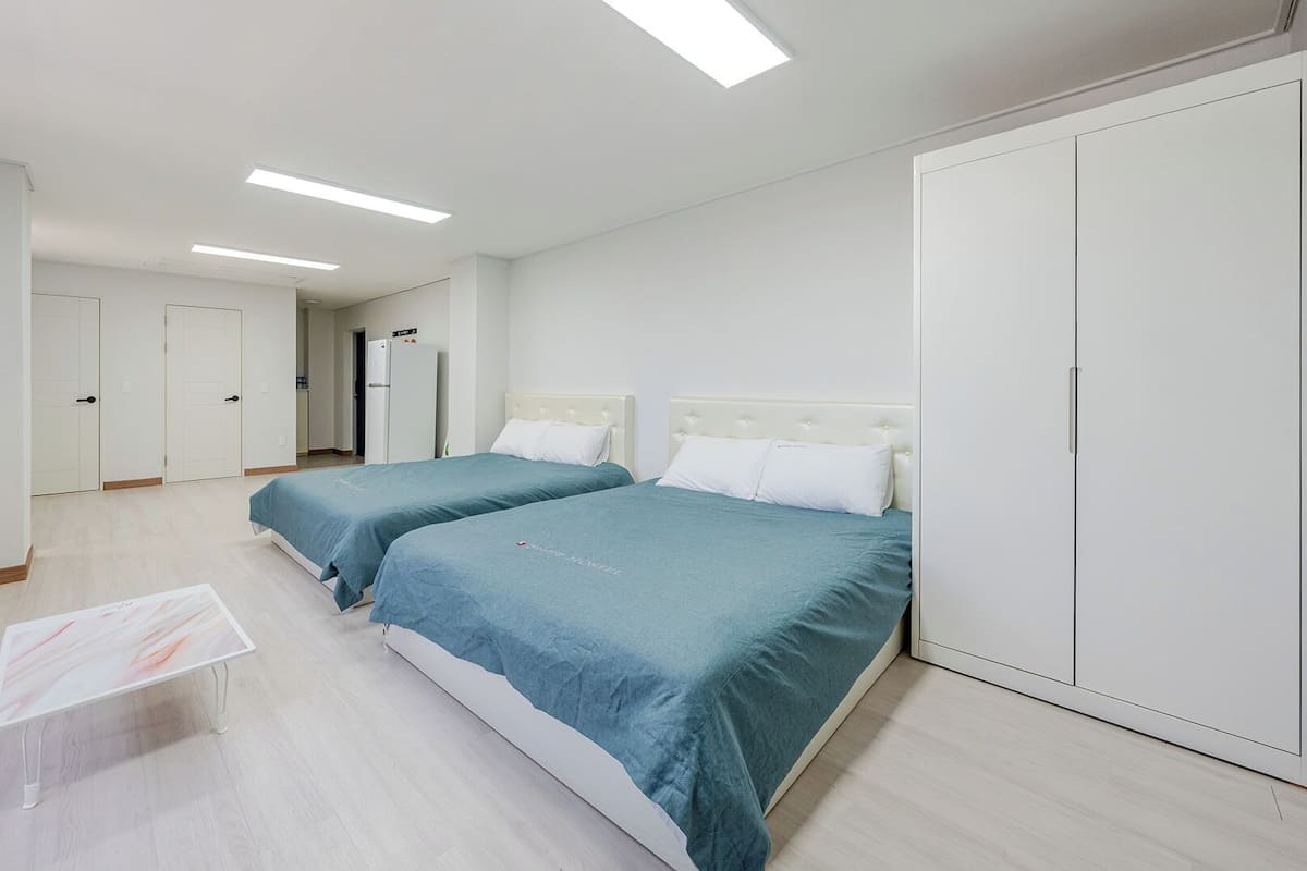 Habitación de hotel con dos camas, un armario, un escritorio y una ventana con persianas.