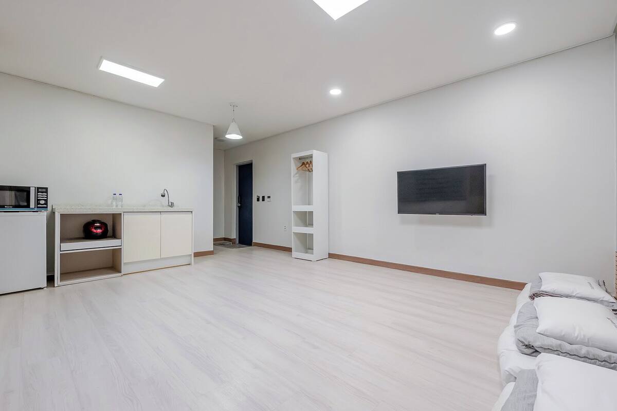 Una habitación moderna y minimalista con kitchenette, televisor de pantalla plana y cama.