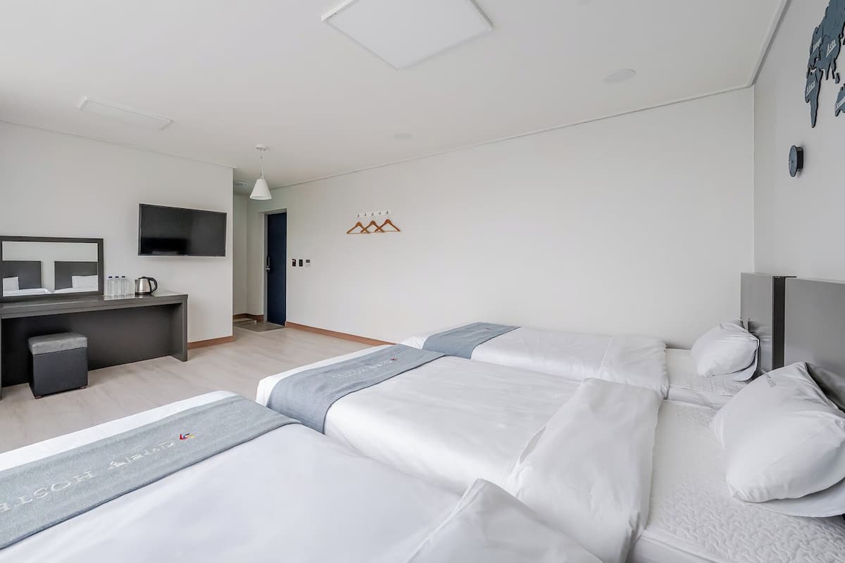 Una habitación de hotel moderna con cama, mesitas de noche, escritorio, televisor y armario.