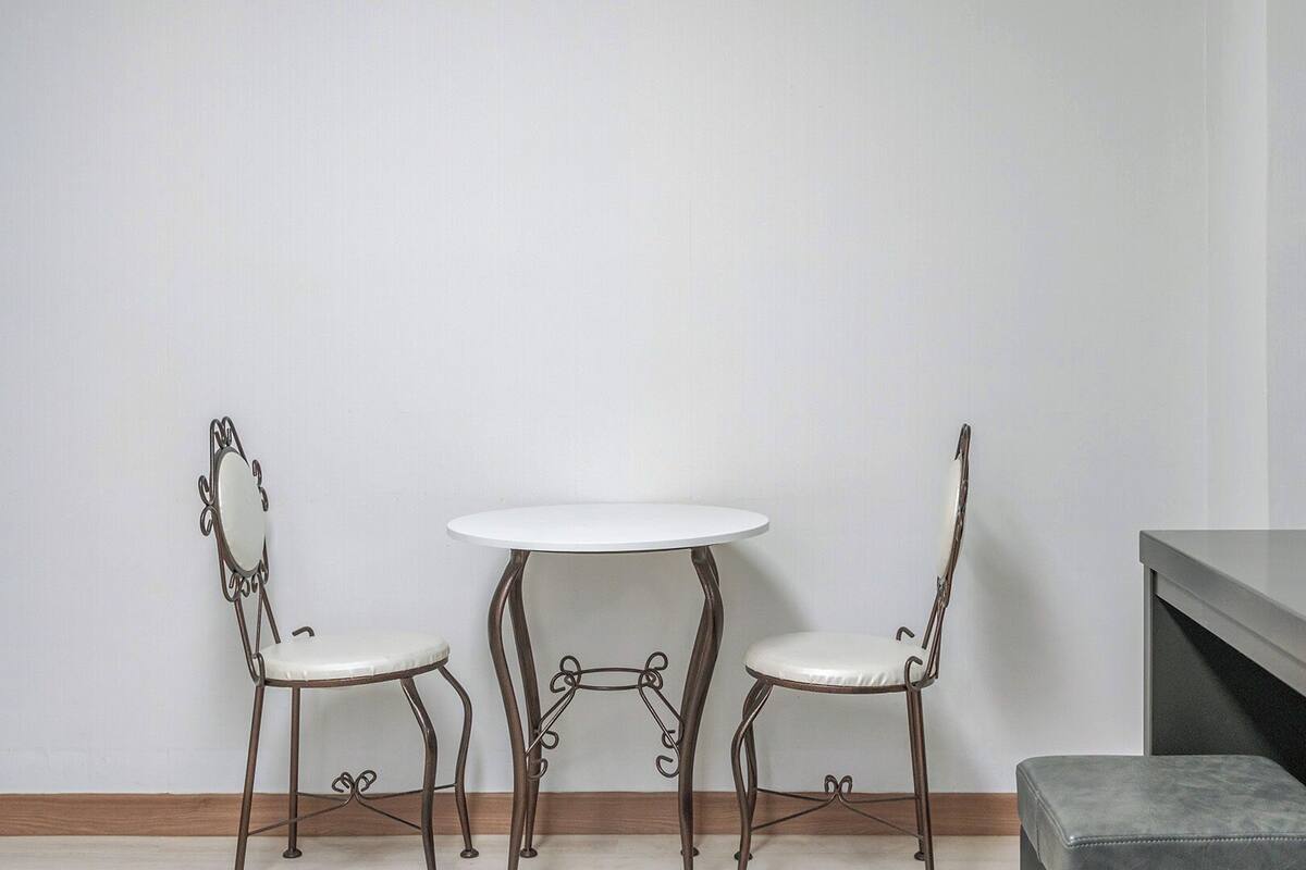 Una mesa pequeña y redonda con dos sillas, un espejo y un banco.