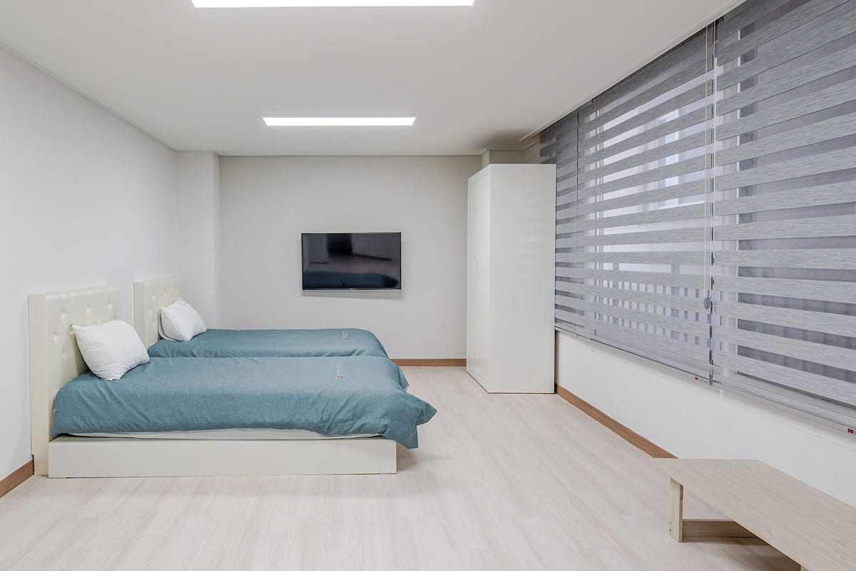 Un dormitorio moderno con dos camas, un televisor y un armario.