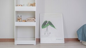 Ein weißes Regal mit einem Glasbehälter, einem aufgerollten Handtuch und einem knochenförmigen Gegenstand.