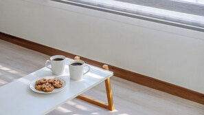 Una mesa blanca con dos tazas de café blancas y un plato de galletas.