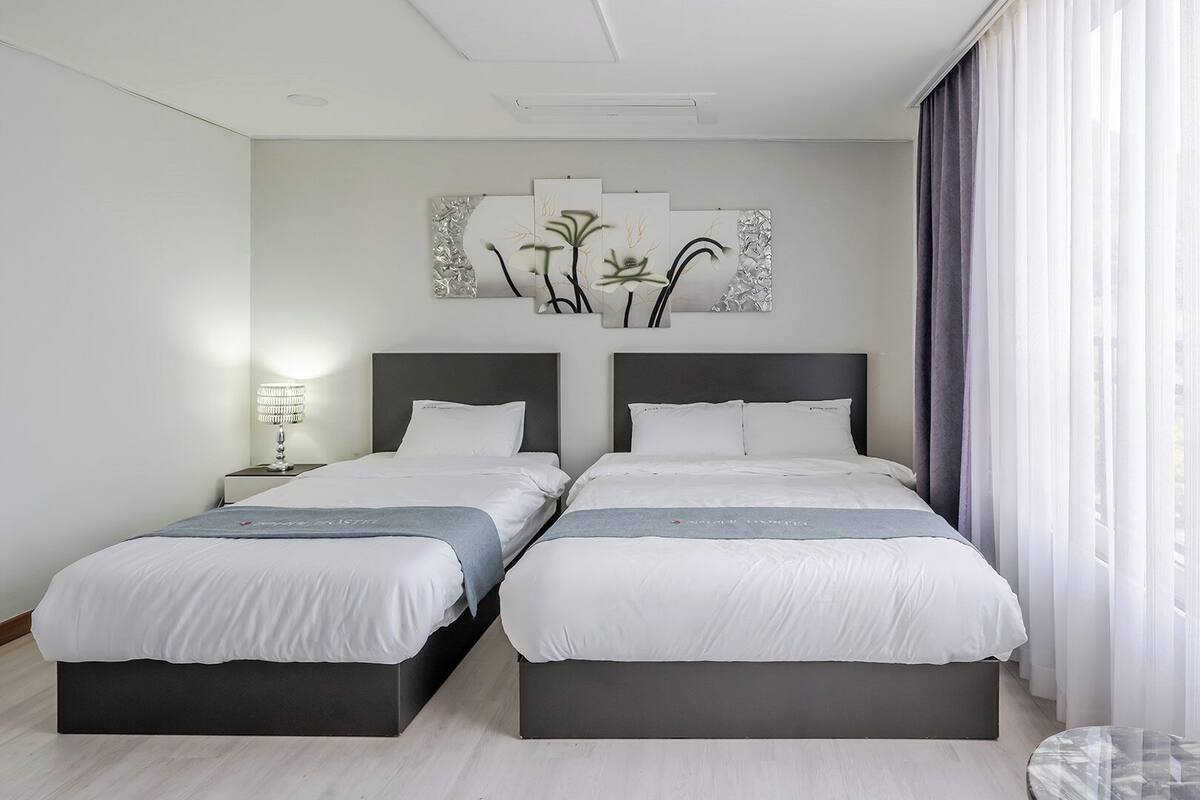 Habitación doble con una ventana grande y una obra de arte colgada en la pared.