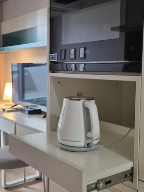 Eine Küchenzeile mit Kaffeemaschine, Mikrowelle und kleinem Kühlschrank.