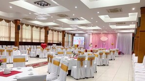 A banquet hall with round tables, white tablecloths, and gold sashes. - Nha Khach TW (Hanoi)