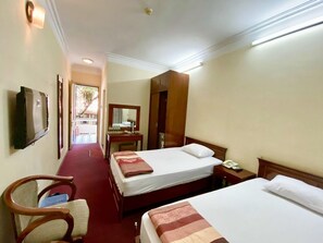 Ein Hotelzimmer mit zwei Betten, einem Fernseher, einem Schreibtisch und einem Stuhl.