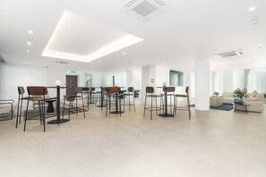 Eine moderne Hotelhalle mit einer zentralen Sitzecke, einem Empfangsbereich und einer Couch im Hintergrund.