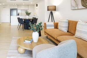 A modern living room with a sofa, coffee table, and a dining area with chairs and a table.