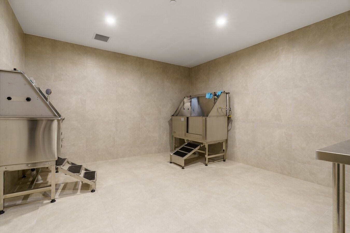 A clean, industrial-style room with a kitchenette area, including a stainless steel appliance and a food processing machine.