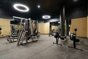 Ein Fitnessraum mit verschiedenen Trainingsgeräten, Holzpaneelen und einem gefliesten Boden.