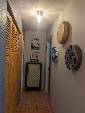 A hallway with a ceiling fan, a framed picture, a cabinet, and wall art.