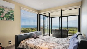 Ein Schlafzimmer mit Bett, Fenster und einem Balkon mit Meerblick.