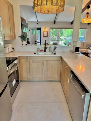 A modern kitchen with wooden cabinets, a large island, a built-in oven, and a coffee maker. - Spacious, beautiful 5 Bed, 2.5 Bath modern house in Saint Paul for extended stay (Saint Paul)