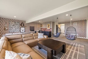 A spacious living room with a large sofa, a coffee table, and a hanging chair.