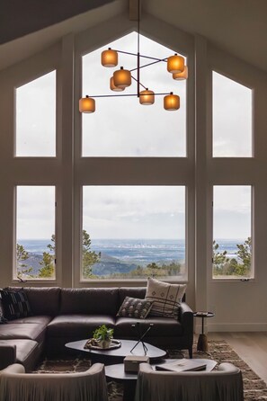 A modern living room with a sectional sofa, a coffee table, and a view through large windows.