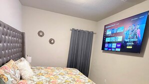 Ein Schlafzimmer mit einem Bett, einem an der Wand befestigten Fernseher und einer Deckenleuchte.