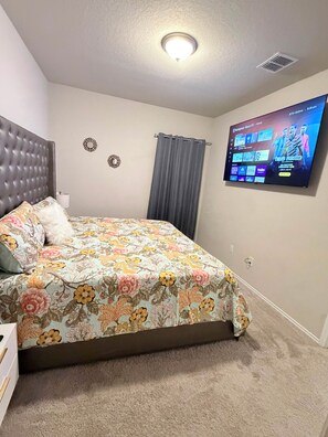 Ein Schlafzimmer mit einem Bett, einem an der Wand befestigten Fernseher und einer Deckenleuchte.