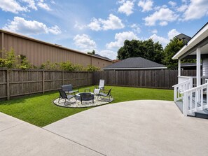 A backyard with a fire pit, outdoor seating, and a wooden fence. - Group Duplex near NRG with 7-Car Gated Parking (Houston)